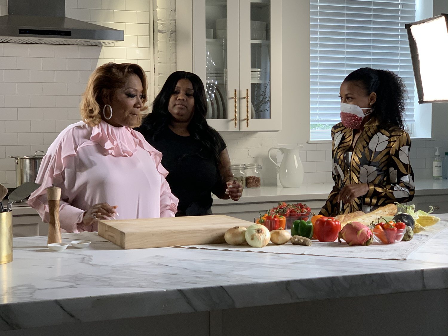 Chelsea coaching Patti LaBelle at a kitchen set for her commercial