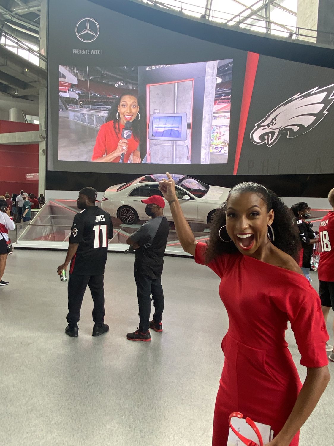 Chelsea pointing excitedly at a giant stadium screen showing herself live on camera