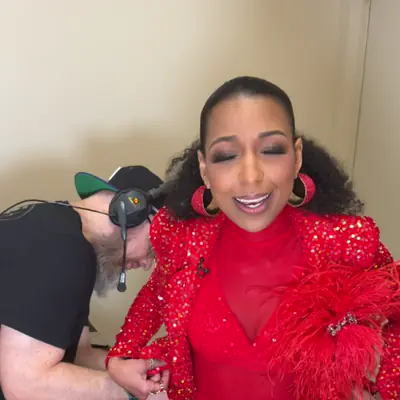 Looping clip: Chelsea laughing in red sequins while getting mic'd up backstage